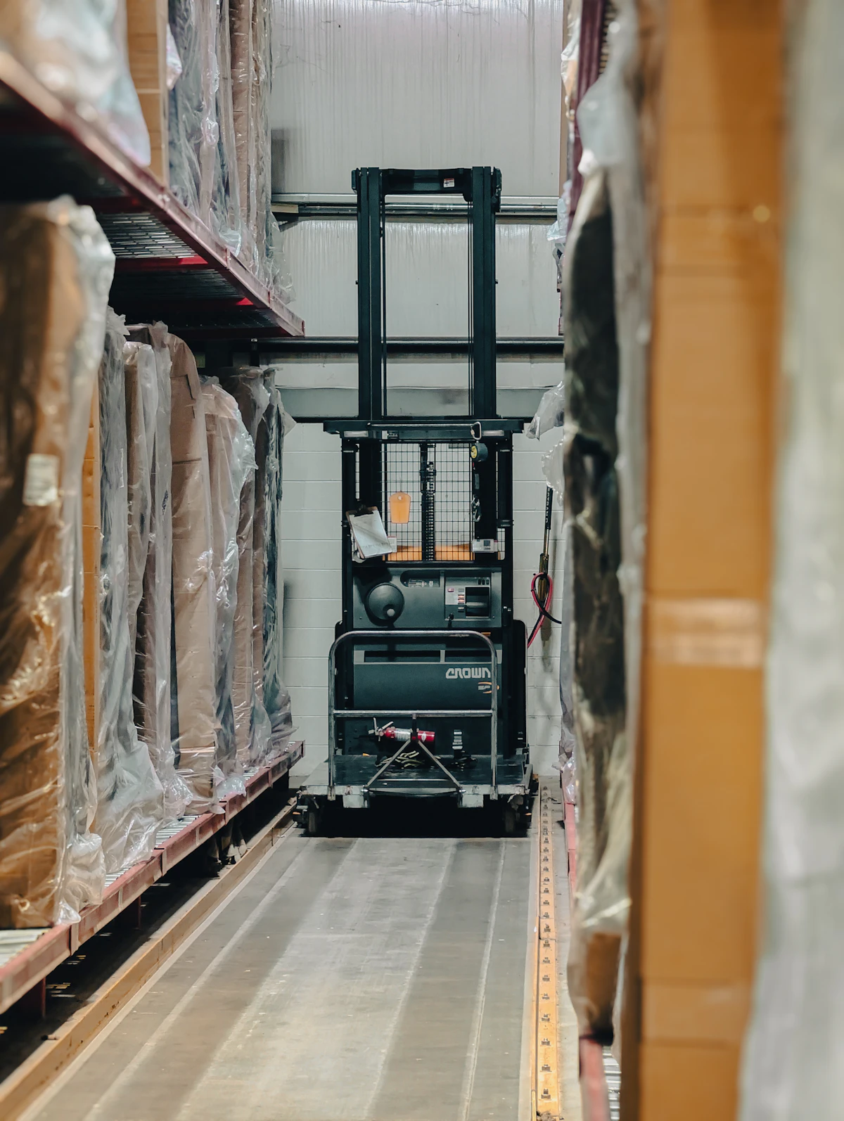 Warehouse aisle with shelves of inventory and a forklift